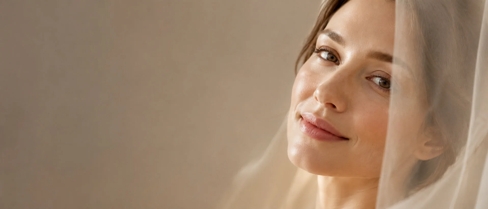 A woman with a soft veil smiling in warm light